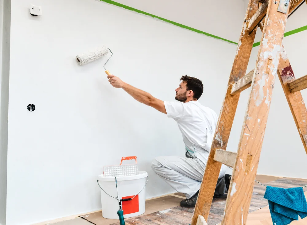 Application de peinture blanche au rouleau sur un mur intérieur